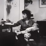 A woman sits with her baby in her arms
