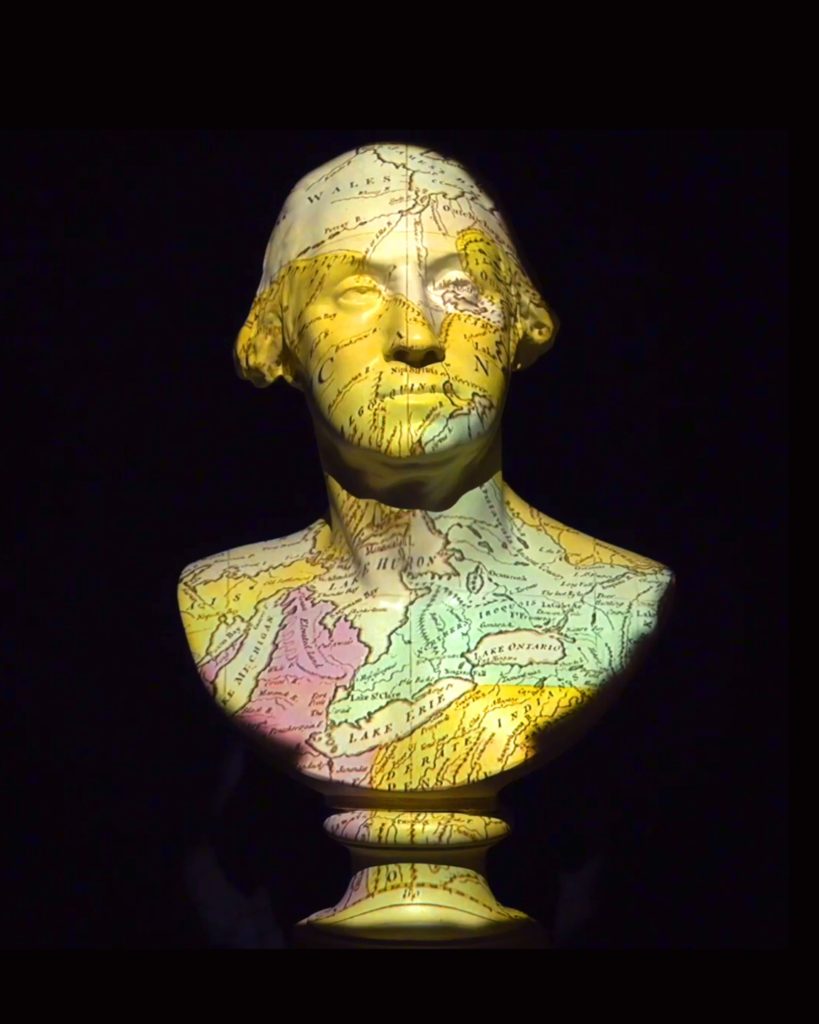 Sculpture of George Washington with a colorful map projected onto it