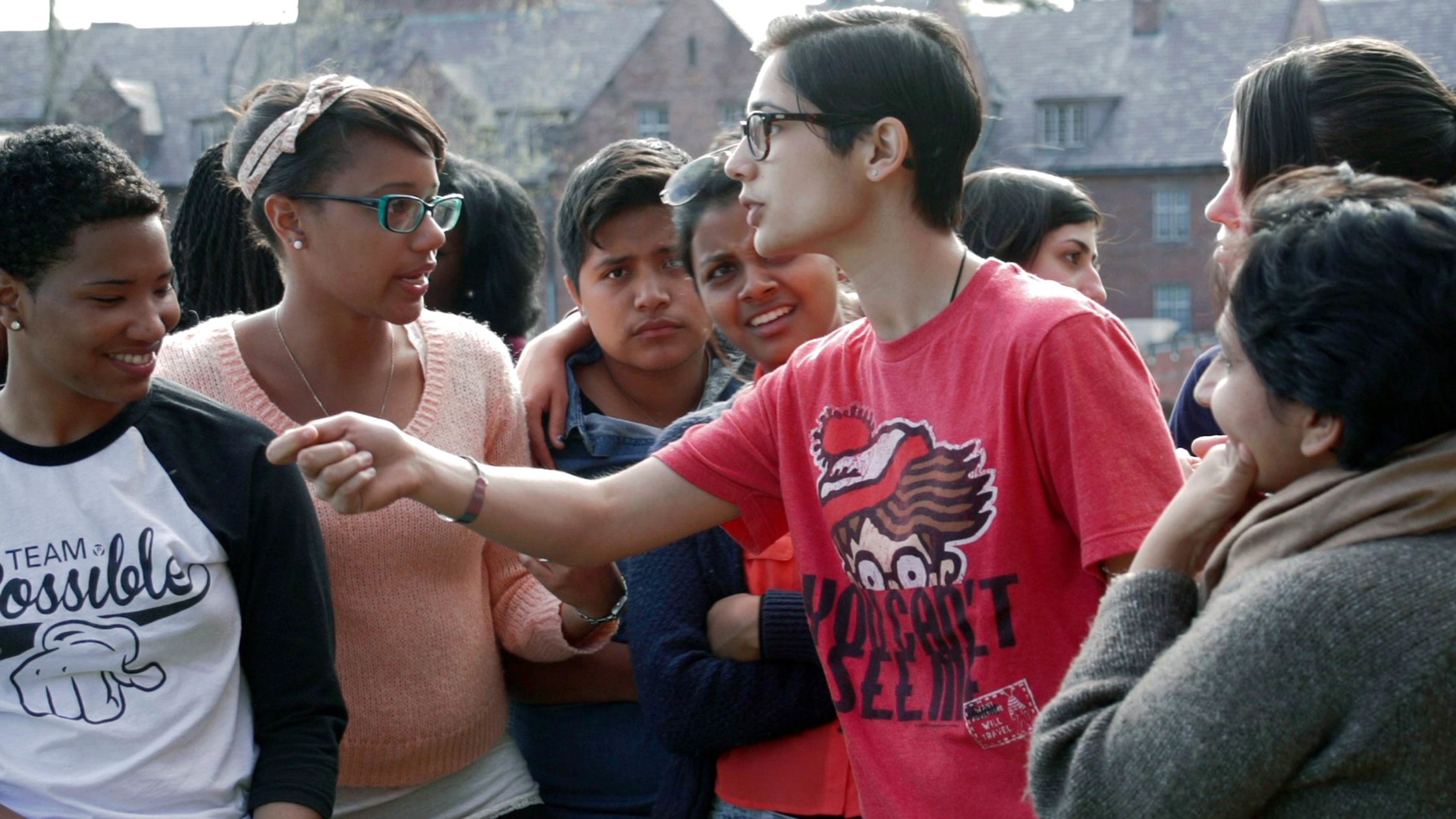 a young person wearing a Where's Waldo tshirt holds a microphone out to a group of teens