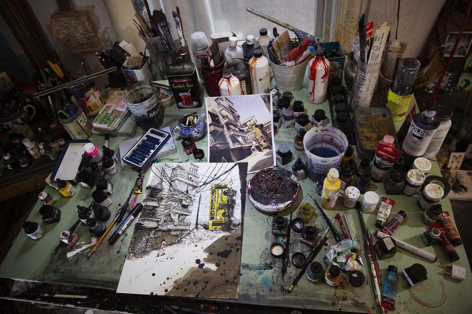 An artist's table covered with materials and a half finished piece